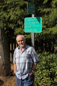 Barry Mathias at car stop sign, Pender Island BC